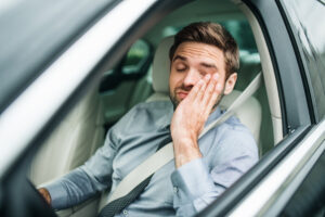 Man in car looking tired and sleepy.