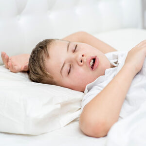 Child sleeping peacefully on white bed.